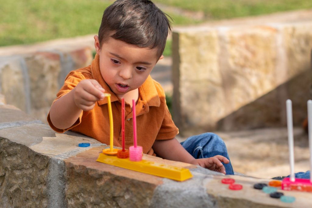 A young boy engaging in play with toys in a sandbox.