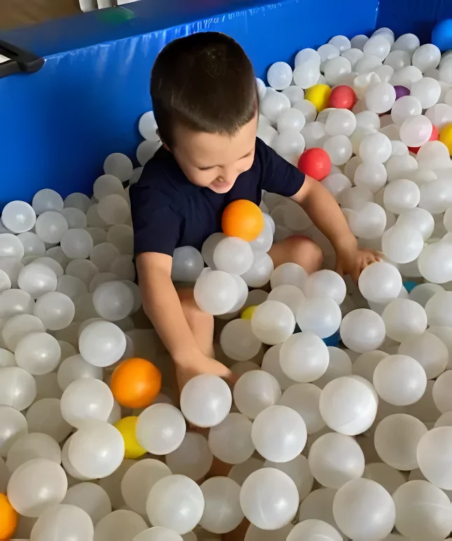 A young boy enjoying a fun-filled playtime in a ball pit.