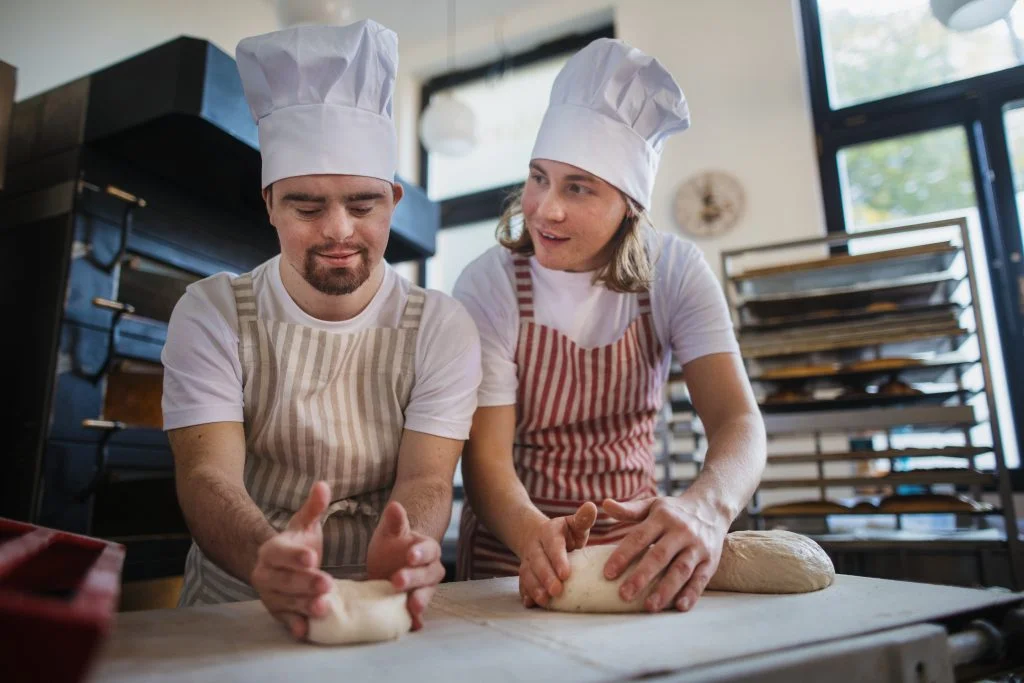 Two bakers preparing dough in a bakery for NDIS goods.