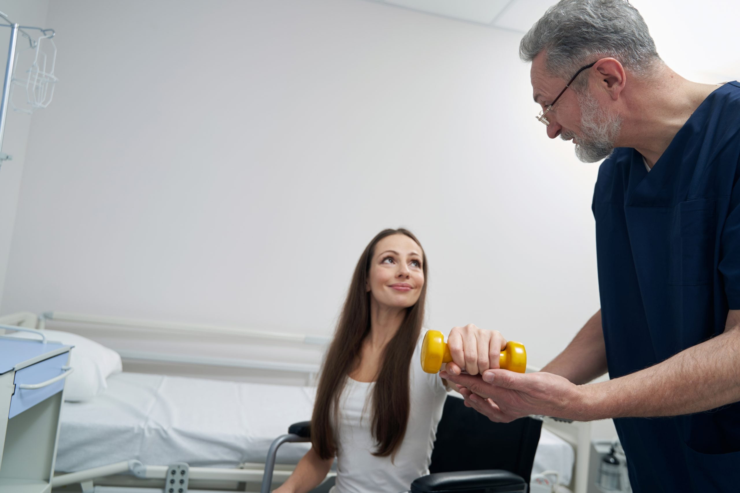 A male doctor is assisting a woman in a hospital room.